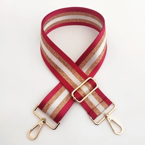 Detail of a 5cm wide striped shoulder strap with red white gold colors and metal hooks