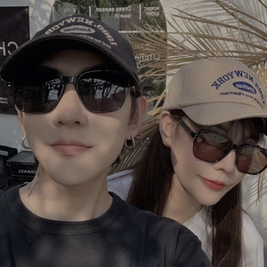 Couple wearing trendy oversized black square sunglasses and stylish baseball caps