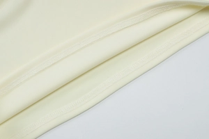 Gros plan détaillé de l'ourlet à double couture et texture côtelée sur ensemble beige