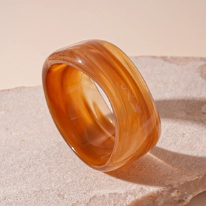 Macro view of wide resin ring featuring amber and cream marbled texture on stone