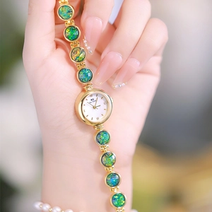 Close-up of golden bracelet watch featuring green malachite texture dial on a female wrist