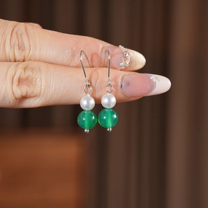 Vista macro di orecchini vintage con perle bianche e perline di agata verde su ganci argento