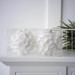 Macro shot of two white glittery petal Christmas ball ornaments in a clear gift box