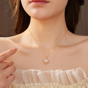 Detailansicht einer goldenen Kleeblatt-Halskette mit Zirkonia am Hals eines Models