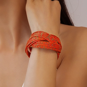 Detail of bohemian multilayer orange glass seed bead bracelet on a model's wrist