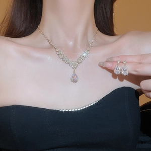 Close-up of golden teardrop zircon necklace and earrings set worn by a model