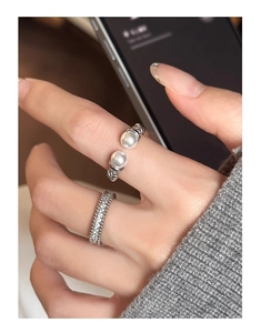 Close-up of adjustable silver pearl ring and sparkling pave zircon band on a model hand