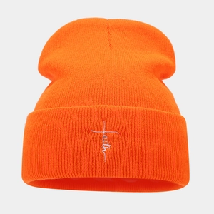 Close-up of bright orange ribbed knit beanie with white Faith cross embroidery detail