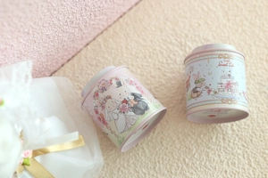 Detailed view of pink and light blue bunny tin cans on soft fabric for gift packaging