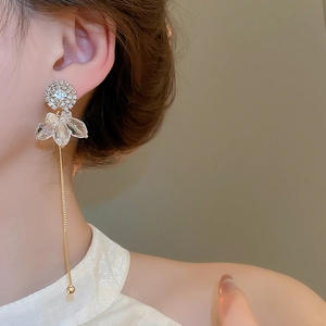 Detail shot of long gold flower tassel earrings with crystals on an elegant model