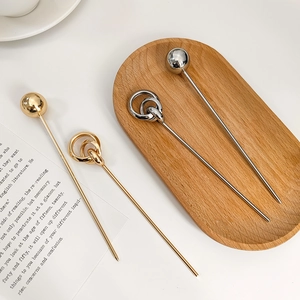 Detailed view of minimalist gold and silver geometric metal hair sticks on a tray