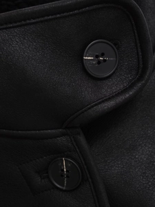 Detailed macro view of black faux suede jacket featuring two classic four-hole buttons