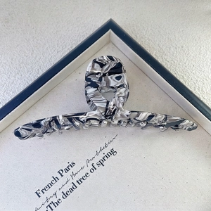 Top view of a large black and white marble acetate hair claw clip on canvas prop