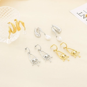 Détail de boucles d'oreilles œil porte-bonheur en V avec perles et métal torsadé