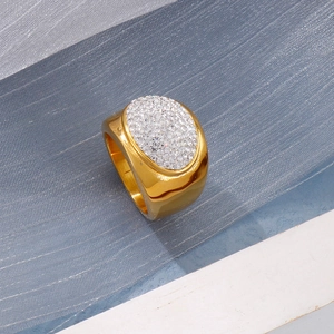 Detail of wide gold ring featuring a sparkling oval face encrusted with white crystals