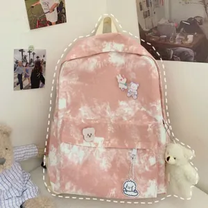 Detail of pink tie-dye canvas backpack with cute plush bear pendant and cartoon badges