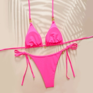 Flat lay of pink bikini with gold star charms and side-tie details for summer beachwear