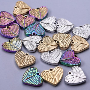 Macro view of winged heart pendants in gold, silver and rainbow stainless steel