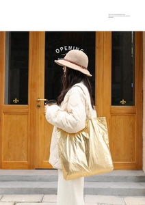 Detailed view of a metallic gold nylon tote bag with crinkled texture and large capacity