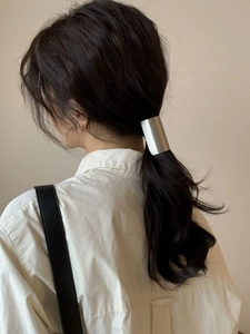Detail of minimalist matte silver metal ponytail cuff on model for elegant hairstyle