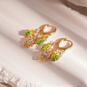 Detail of gold leaf drop earrings with emerald green crystals and sparkling small diamonds