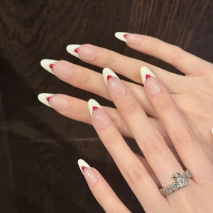 Faux ongles amande faits main avec pointes françaises et motifs cœur rouge sur bois