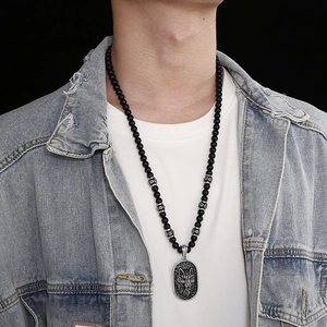 Detail of punk style wolf head pendant with black beaded chain on male model