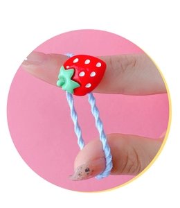 Close-up of a cute red strawberry charm on a light blue elastic baby hair tie