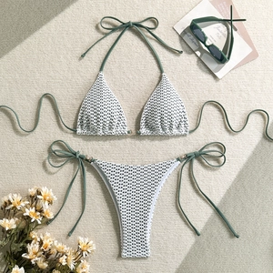 Detail of crochet bikini with gold ring hardware and sage green ties on beige texture