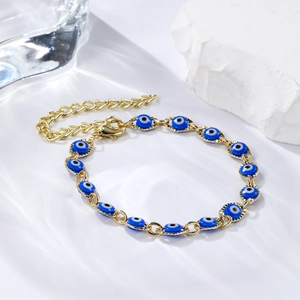 Detailed shot of golden evil eye bracelet with blue enamel charms on water ripple background