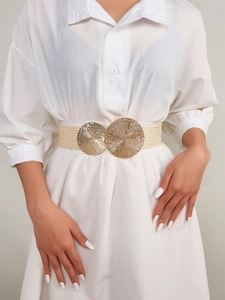 Detail of cream elastic woven belt with dual gold sunburst buckles on a white shirt dress