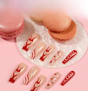 Close-up of coffin-shaped press-on nails with flame hearts and star rhinestones