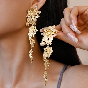 Detail of gold floral leaf earrings featuring crystal accents and vintage metal texture