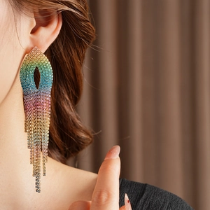 Close-up of model wearing long gradient rainbow rhinestone tassel earrings in soft light