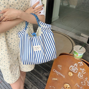 Detailed view of a blue and white striped canvas tote bag with woven rope handles and label