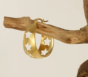 Détail de créoles en or 18 carats avec étoiles ajourées sur une branche en bois