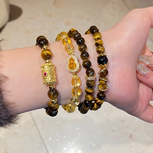 Detail of layered tiger eye and citrine bracelets featuring a crystal gourd charm