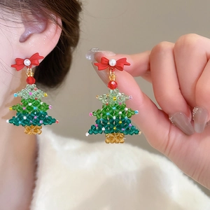 Detail of Christmas tree beaded earrings with green beads and a red bow on model ear