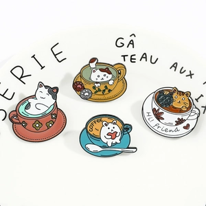Macro detail of four cute cat coffee cup enamel pins on a white ceramic plate decoration