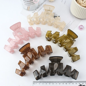 Matte wavy hair claw clips in five assorted colors on a minimalist decorative background