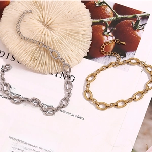 Detail of 14K gold and silver chunky oval link anklets with lobster clasp on a white desk