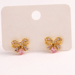 Detail of gold bow earrings with sparkling pink zircons and teardrop gemstone drops