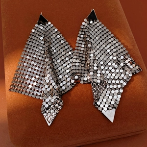 Detailed macro view of silver mesh drop earrings with triangle studs on brown velvet box