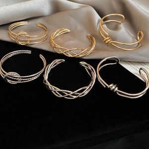 Detailed view of irregular twisted gold and silver metal bangles on silk background