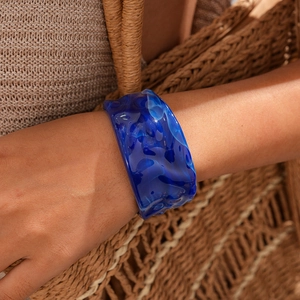 Detail view of dark blue resin bangle with ripple texture on a woman wrist