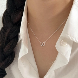 Close-up of a silver heart pretzel knot pendant necklace with zircon on a model