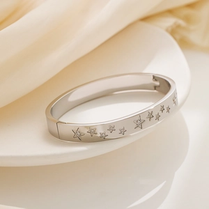 Close-up of silver star-engraved stainless steel bangle with crystal zircon details