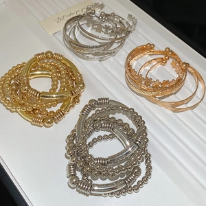 Détail d'un ensemble de six bracelets en métal avec motifs fleurs et étoiles dorés