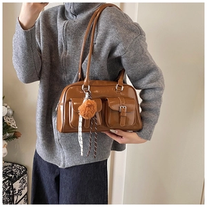 Lifestyle shot of caramel vintage bowling bag with front pockets and furry charm