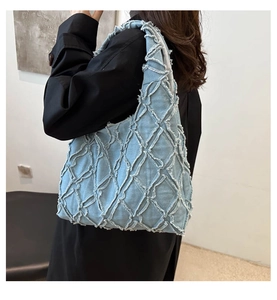 Detail of light blue denim tote bag featuring quilted diamond pattern and frayed edges